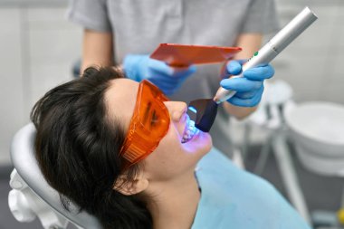 Pretty womans teeth treatment in dental clinic clipart