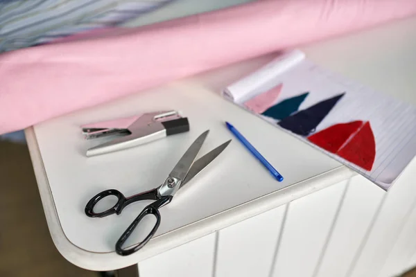 Mesa blanca con rollo de tela y accesorios de costura —  Fotos de Stock