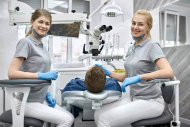 Çalışma sırasında kameraya poz veren neşeli diş hekimleri