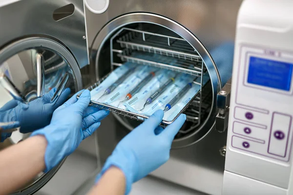 Le dentiste charge des sondes dentaires dans la machine de stérilisation — Photo