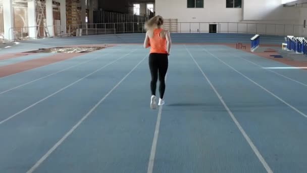 Sportív Blonde nő fut a beltéri stadion — Stock videók