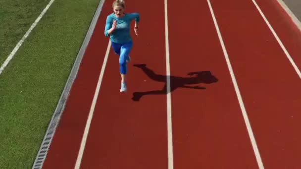 Спортивна блондинка біжить на відкритому стадіоні — стокове відео