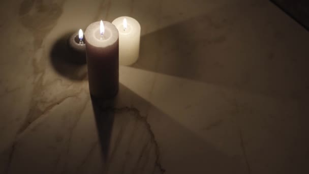 Burning candles on table in dark interior — Stock Video