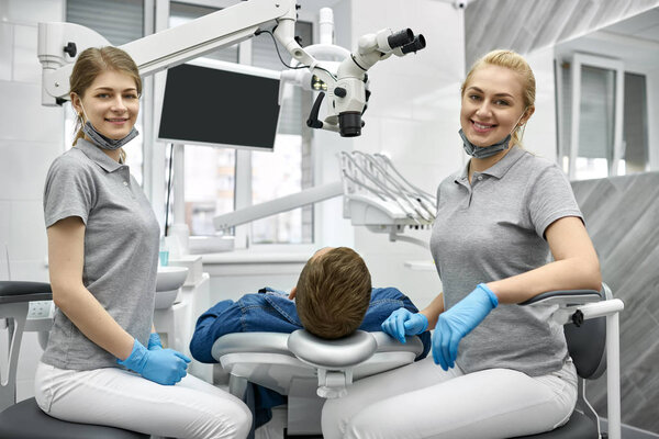 Веселые дантисты позируют перед камерой во время работы
