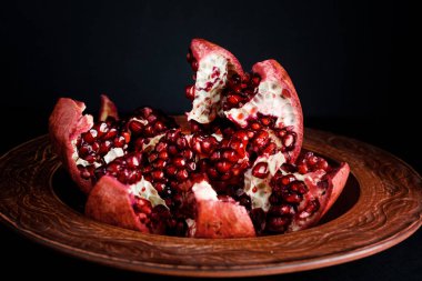 Olgun ve lezzetli nar siyah bir masaya bir tabak içinde
