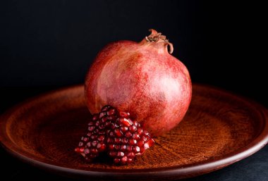 Olgun ve lezzetli nar siyah bir masaya bir tabak içinde