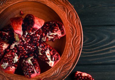 Olgun ve lezzetli nar siyah bir masaya bir tabak içinde