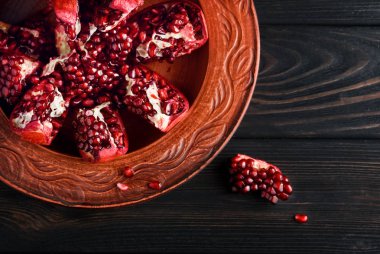  Olgun ve lezzetli nar siyah bir masaya bir tabak içinde