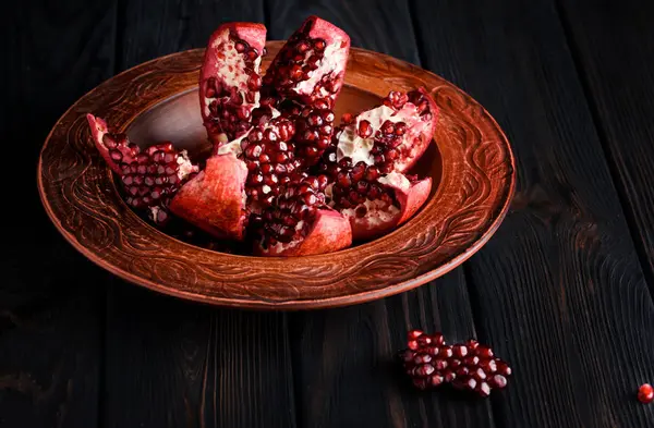 Olgun ve lezzetli nar siyah bir masaya bir tabak içinde
