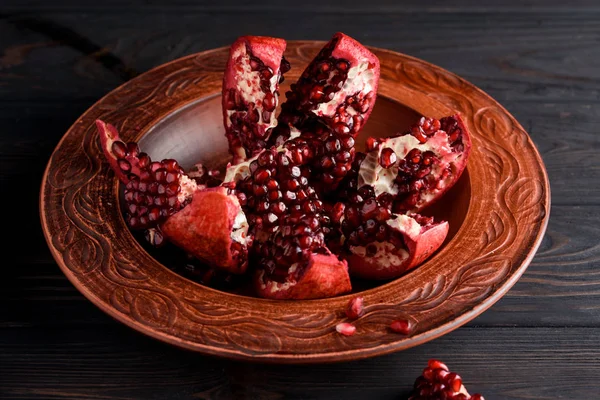 Olgun ve lezzetli nar siyah bir masaya bir tabak içinde