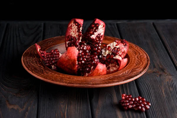 Olgun ve lezzetli nar siyah bir masaya bir tabak içinde