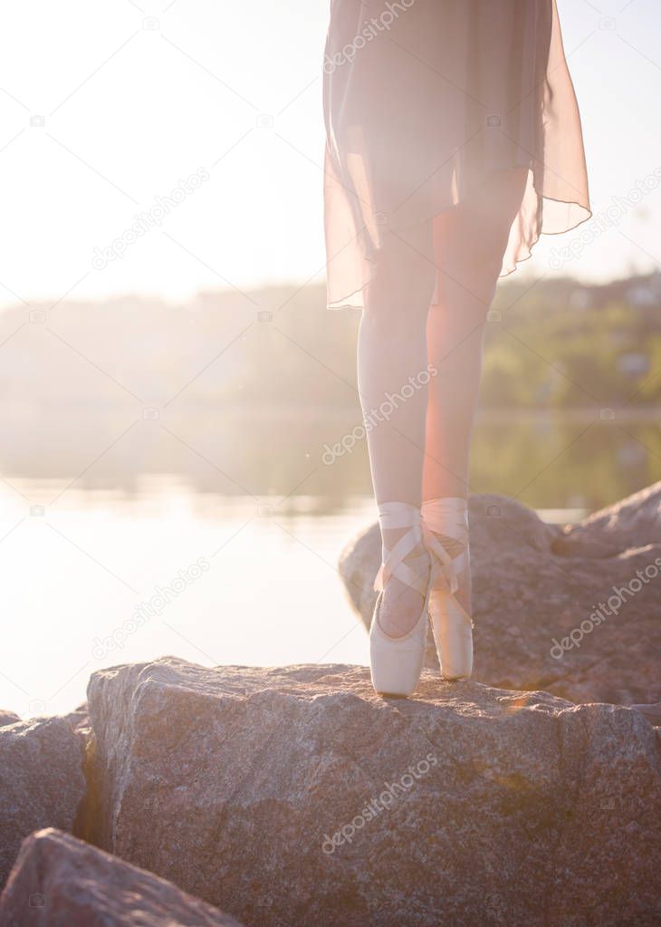 Ballerina in pointe shoes at sunset by the sea