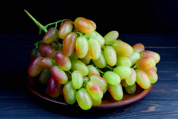 Купка ароматного стиглого винограду в тарілці на столі — стокове фото