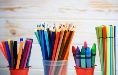 Ahşap arka plan üzerinde yaratıcı çalışma için çok renkli kalemler.