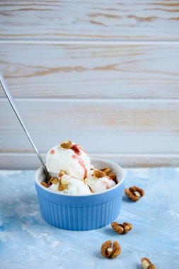 Lezzetli beyaz dondurma ile fındık ve mavi bir arka plan üzerinde meyve şurubu