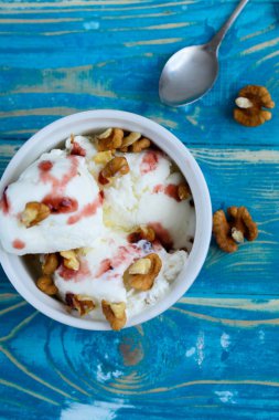 Lezzetli beyaz dondurma ile fındık ve mavi bir arka plan üzerinde meyve şurubu