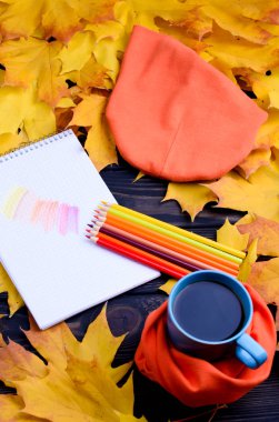 Siyah bir tabloda çay ve renkli kalemler ile sonbahar yaprakları.