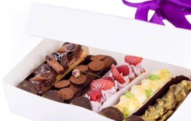 Bir şişe lezzetli tatlılar. Farklı dolguları ile eklerleri. Ambalaj kutusundaki lezzetli tatlılar.