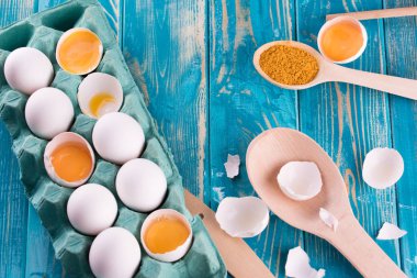 Taze yumurta mavi bir tavada. Taze yumurta baharatlar ile mavi bir tabloda. Ahşap çatal bıçak takımı.