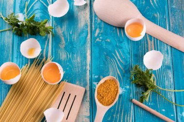 Taze yumurta mavi bir tavada. Taze yumurta baharatlar ile mavi bir tabloda. Ahşap çatal bıçak takımı.