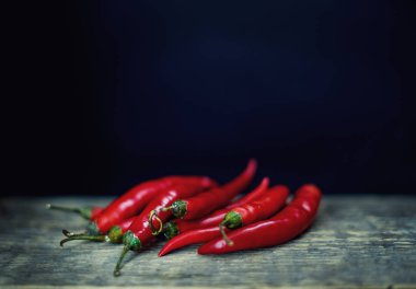 Acı kırmızı biber rustik tarzda bir ahşap tahta üzerinde. Kırmızı acı biber ve koyu arka plan.