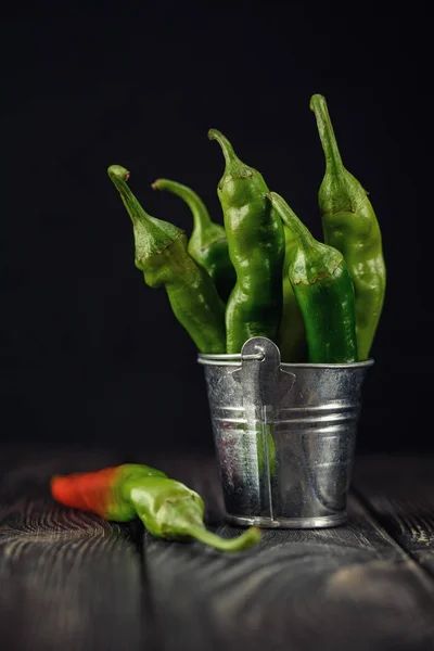 Bitter green pepper in cold tones. Green pepper in a small bucket, Peppers in a bucket on the table.