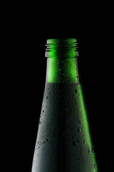 Зелёная стеклянная бутылка на чёрном фоне на фоне света — стоковое фото