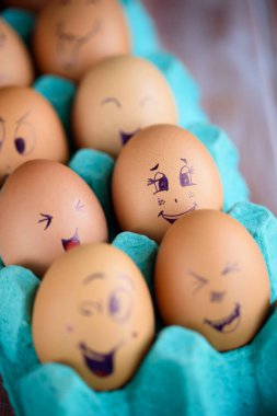 Neşeli çörek üzerinde mavi bir tavada yumurta. Yumurta farklı yüzleri. Duygular.