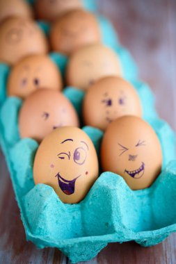 Neşeli çörek üzerinde mavi bir tavada yumurta. Yumurta farklı yüzleri. Duygular.