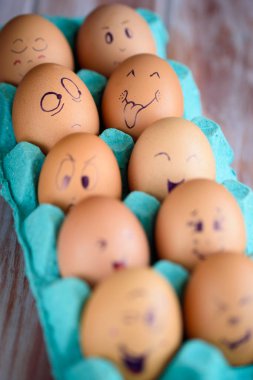 Neşeli çörek üzerinde mavi bir tavada yumurta. Yumurta farklı yüzleri. Duygular.