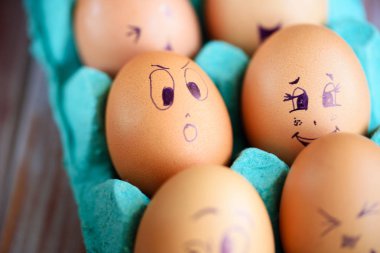 Neşeli çörek üzerinde mavi bir tavada yumurta. Yumurta farklı yüzleri. Duygular.