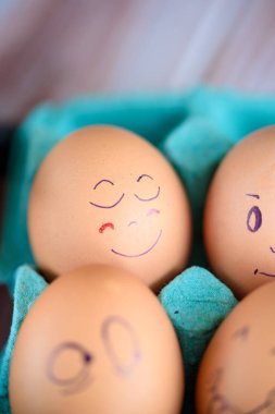 Neşeli çörek üzerinde mavi bir tavada yumurta. Yumurta farklı yüzleri. Duygular.