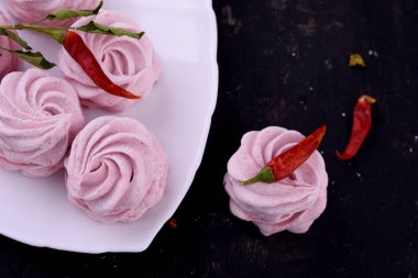 Lezzetli, lezzetli, pikatny tatlı. Marshmallow ile siyah bir zemin üzerine kırmızı biber lezzet.