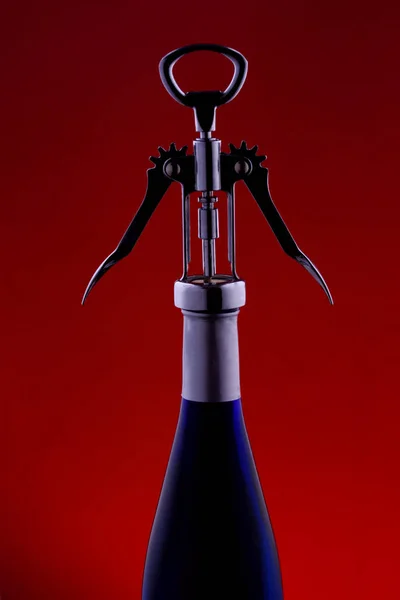 色付きの背景の暗いキーにらせん状の青いガラス瓶 ワインのボトル — ストック写真