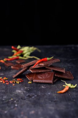 Doğal siyah çikolata siyah bir zemin üzerine kırmızı acı biber ile.