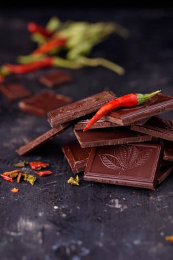 Doğal siyah çikolata siyah bir zemin üzerine kırmızı acı biber ile.