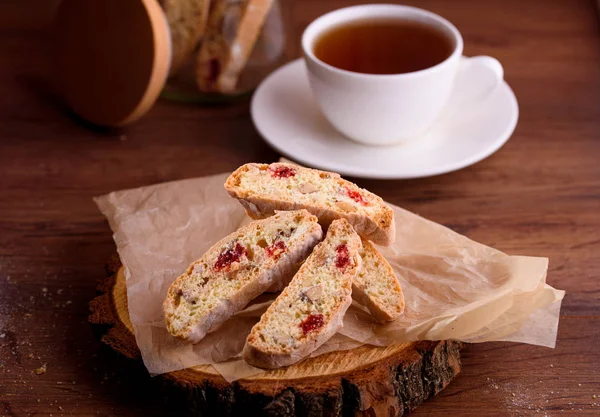 Delicious biscotti cookies with dried cherries and hazelnuts with black tea and white cup. Organic style. White cup of tea.