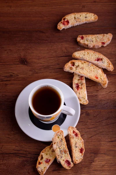 Delicious biscotti cookies with dried cherries and hazelnuts with black tea and white cup. Organic style. White cup of tea.