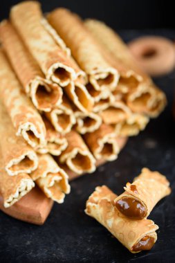 Gofret, lezzetli ve güzel kokulu haşlanmış yoğunlaştırılmış süt siyah bir tablo ile rulo