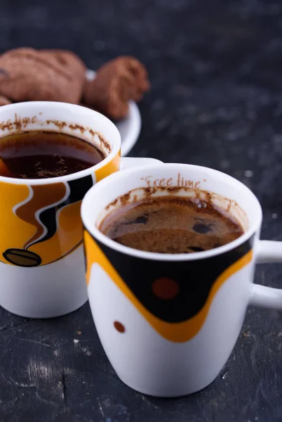 Delicious and fragrant coffee in the form of coffee, with grains of coffee, and small coffee cups on a black background