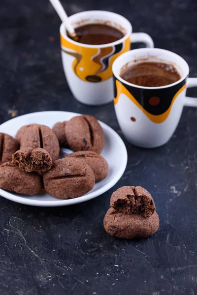 Delicious and fragrant coffee in the form of coffee, with grains of coffee, and small coffee cups on a black background