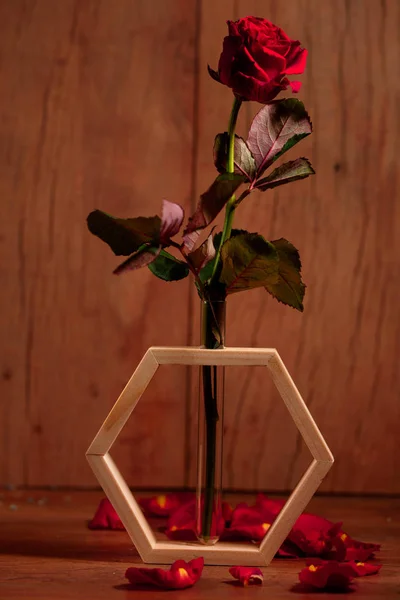 Красная роза в вазе на деревянном столе — стоковое фото
