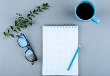 Telefon, gözlük, kalem, kahve, arka planda defter.