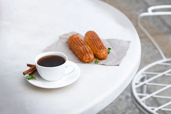 Fragrant coffee with eclairs in the summer cafe. — Stock Photo, Image