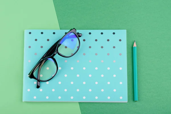Modrý notebook s tužkou, sklenicemi na zeleném pozadí — Stock fotografie