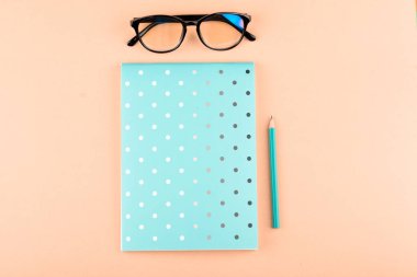 Renkli bir arka plan üzerinde bir kalem, gözlük, ile güzel mavi defter.