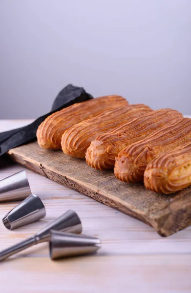 Eclares saborosos e bonitos em um tabuleiro de madeira. Sobremesa apetitosa. Abastecimento — Fotografia de Stock