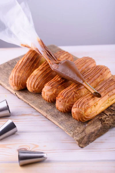 Eclares saborosos e bonitos em um tabuleiro de madeira. Sobremesa apetitosa. Abastecimento — Fotografia de Stock