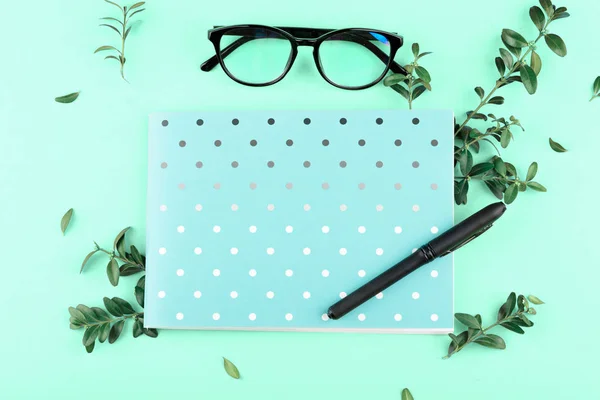 Blå anteckningsbok i en cirkel med en penna, glas, gröna blad, — Stockfoto