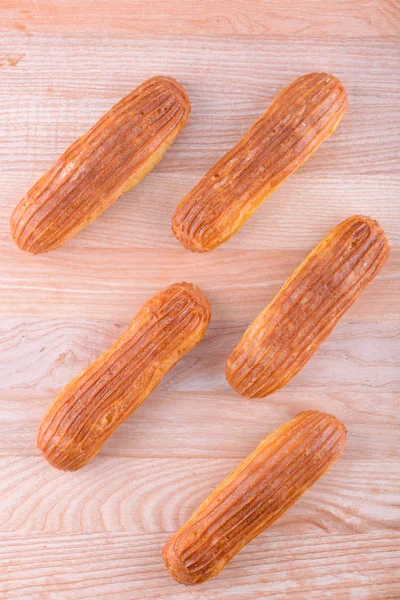 Deliciosas y hermosas eclairs en una tabla de madera — Foto de Stock